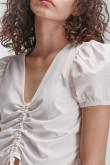 Blusa crema clara manga corta englobada con recogido en frente