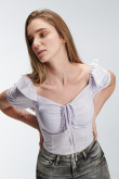Blusa escotada y ajustada en tela fluida de color sólido, con hombros encauchados.