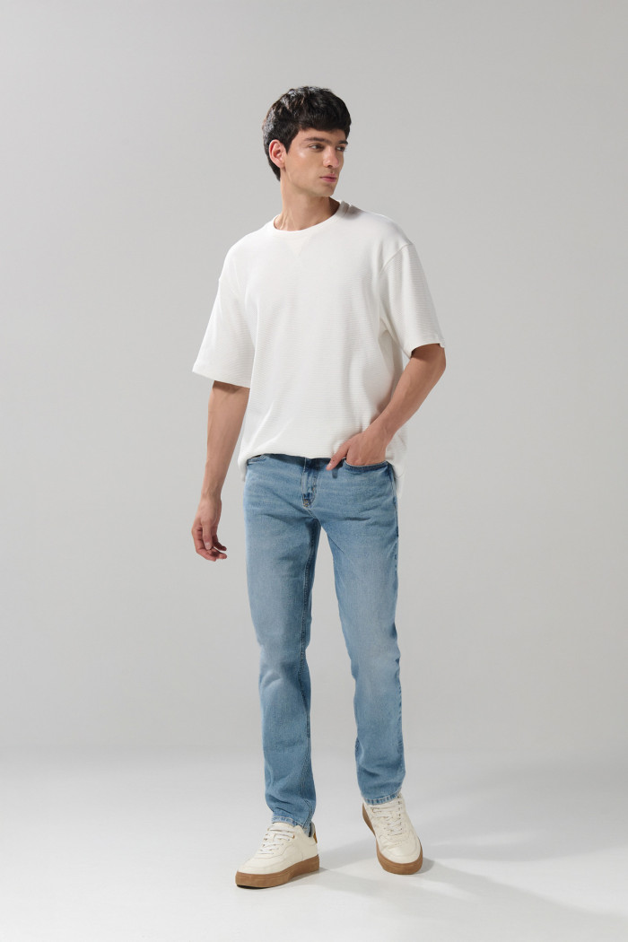 Jean azul claro slim con desgastes ligeros y tiro bajo