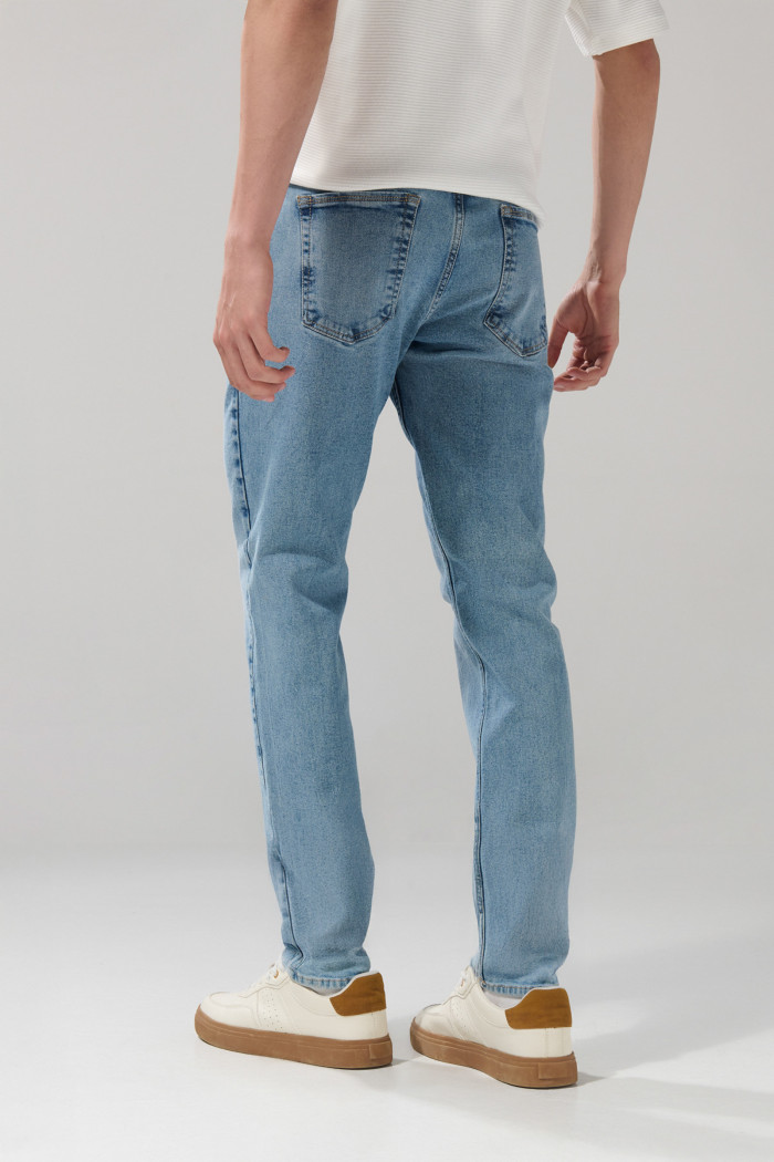 Jean azul claro slim con desgastes ligeros y tiro bajo