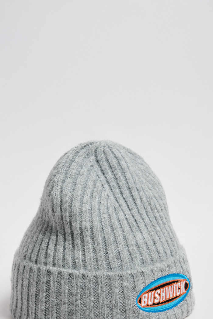 Gorro tejido unicolor con texto en frente y finas texturas
