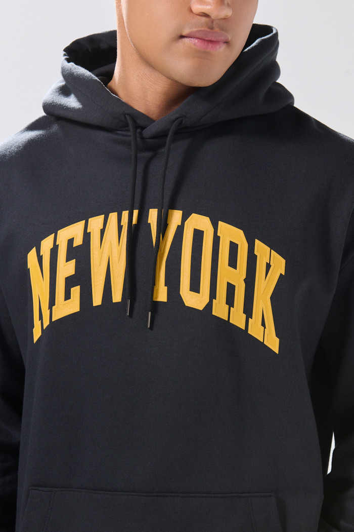 Buzo negro con capota oversize y texto college en frente
