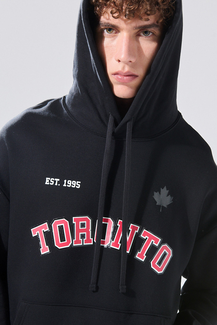 Buzo oversize negro con capota y texto rojo college
