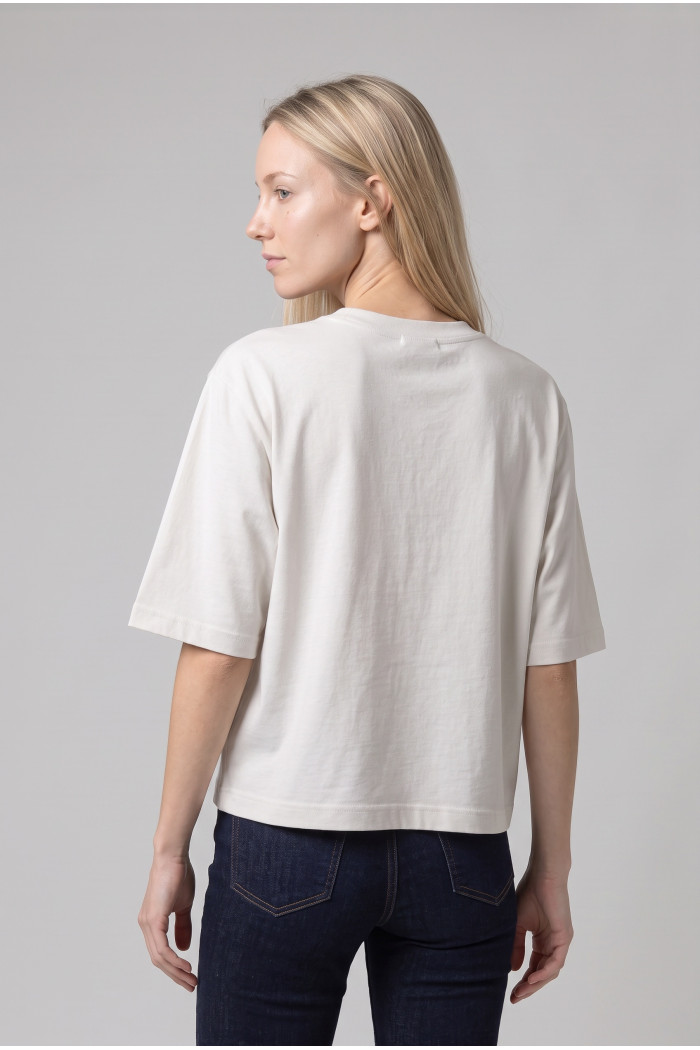 Camiseta crema crop top oversize con diseño en frente
