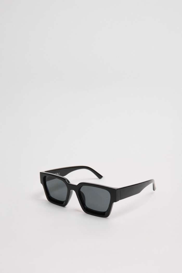 Gafas de sol con marco rectangular en color negro y lentes esfumados en contraste.
