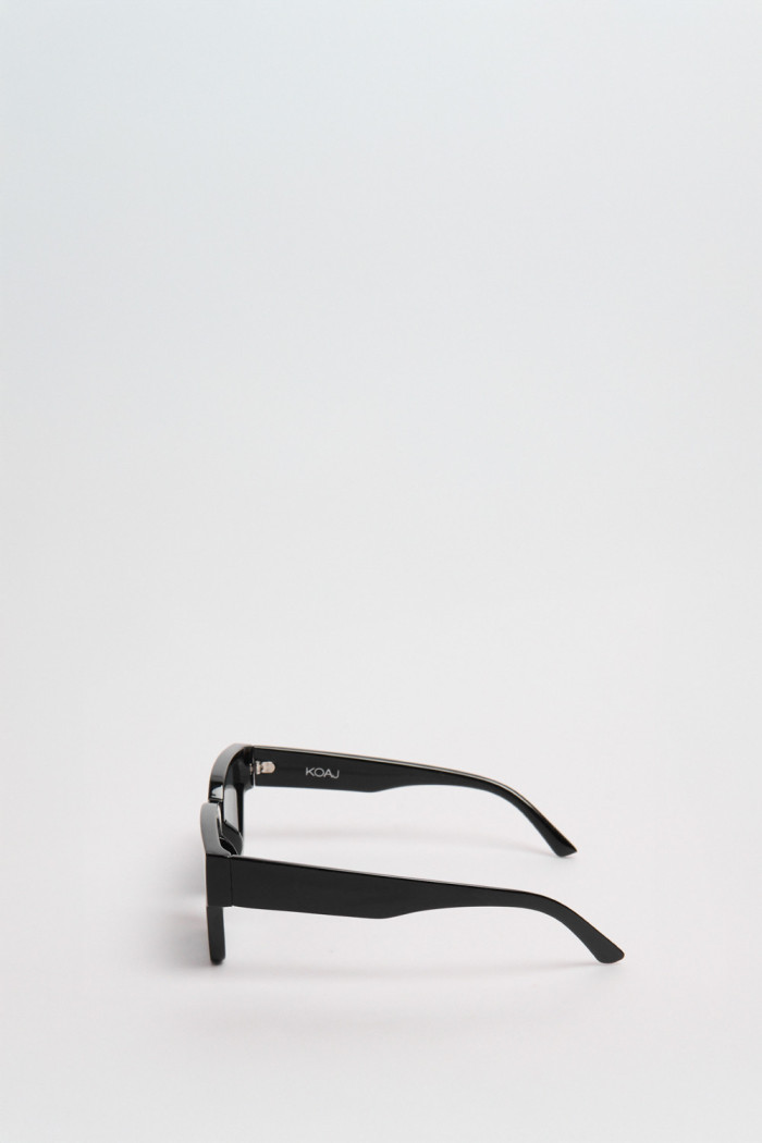 Gafas de sol con marco rectangular en color negro y lentes esfumados en contraste.