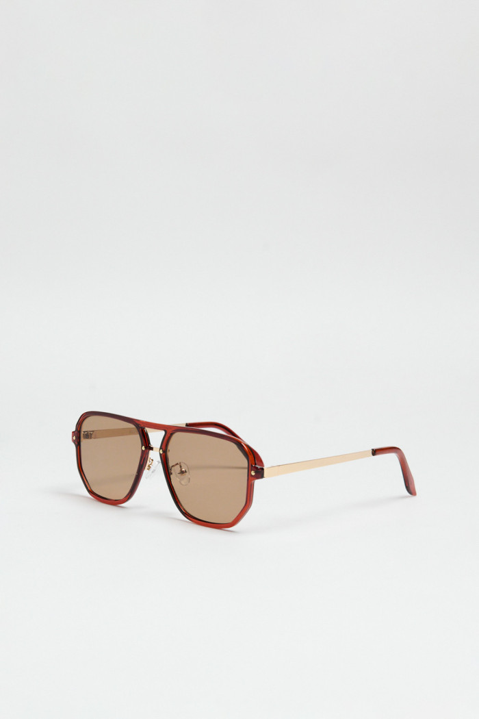 Gafas de sol con marco rectangular café y lentes esfumados en contraste.