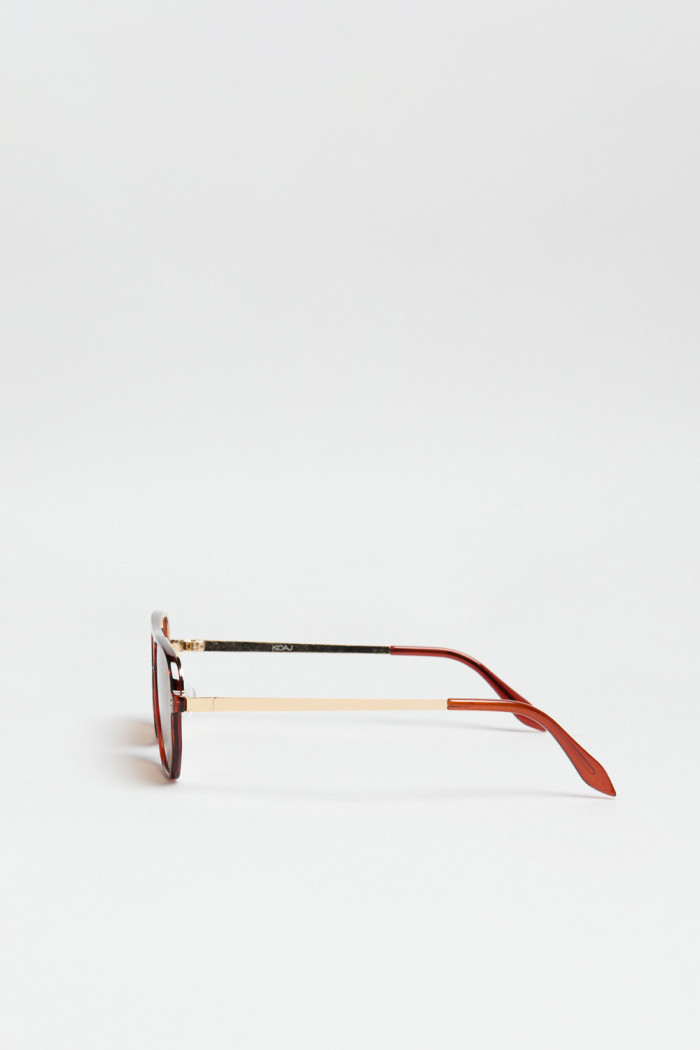Gafas de sol con marco rectangular café y lentes esfumados en contraste.