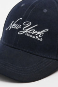 Gorra beisbolera en color azul, con refuerzo, cierre plástico y aplique bordado "New York".