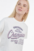 Camiseta crema clara crop top con diseño college lila en frente