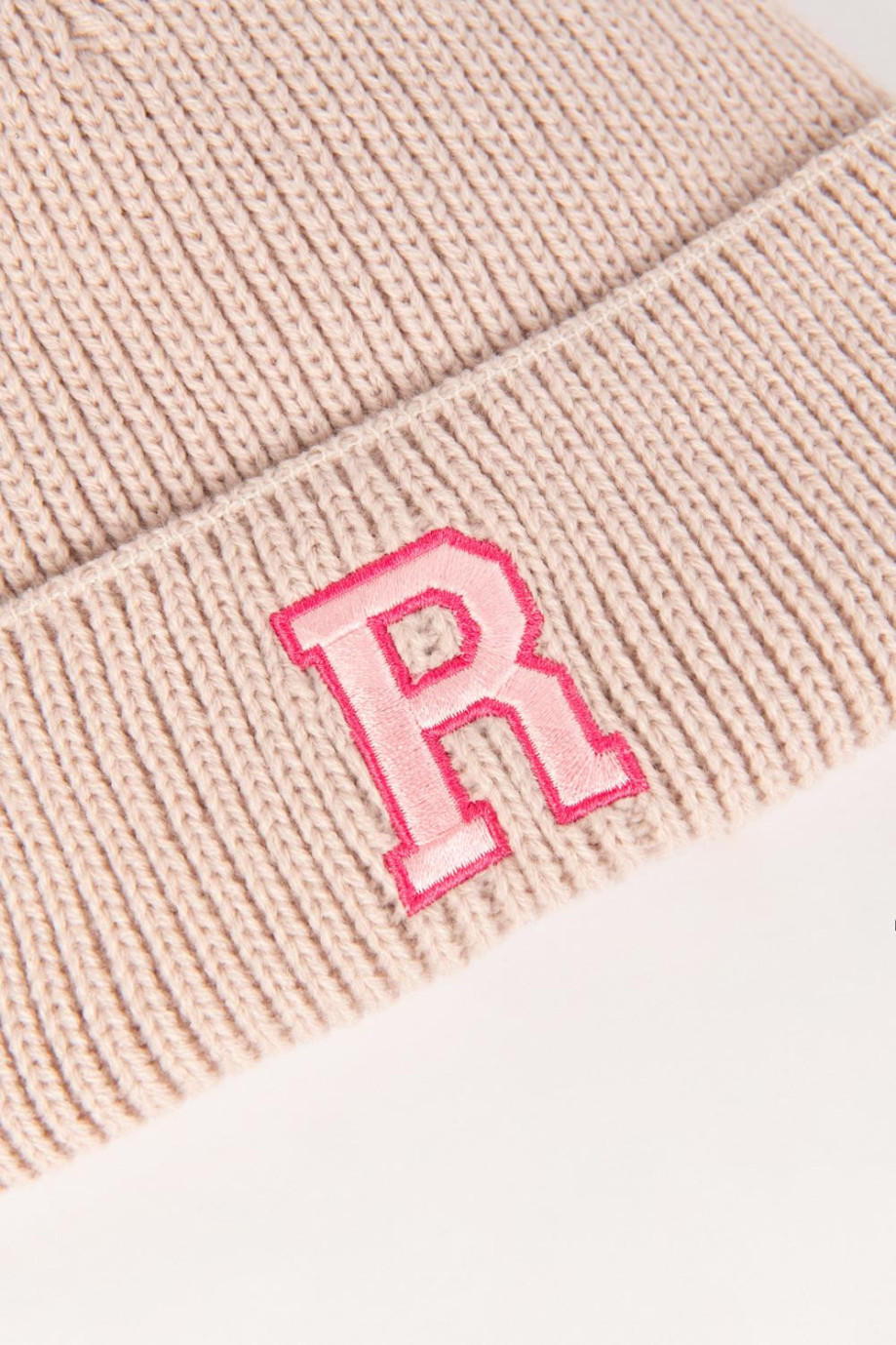 Gorro tejido rosado claro con diseño de letra college en frente