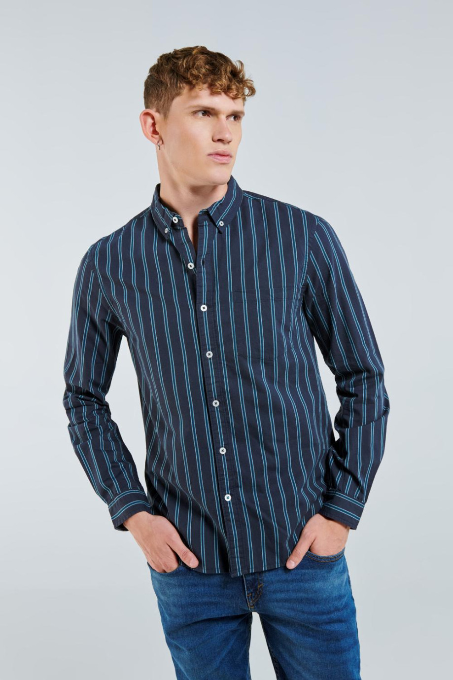 Camisa en slim fit manga larga en rayas con fondo azul oscuro.