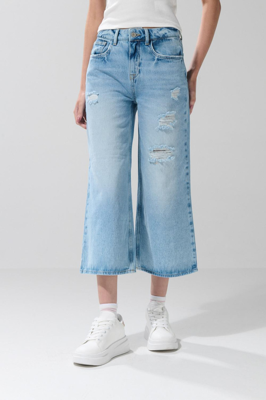Jean culotte azul claro con tiro alto, bota ancha y rotos