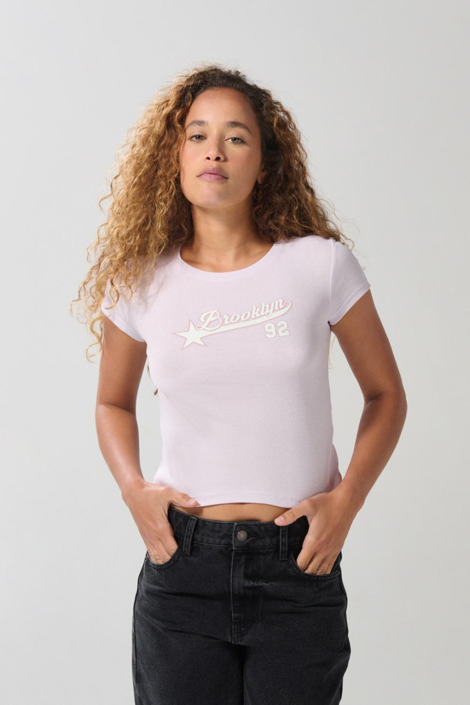 Camiseta para mujer en tela acanalada, cuello redondo y manga corta. Silueta ajustada con arte estilo college