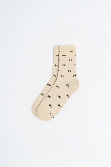 Medias largas crema con diseño de moños.
