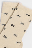 Medias largas crema con diseño de moños.