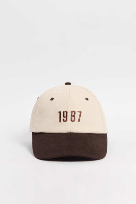 Cachucha con refuerzo, contraste en visera, ojales y botón, cierre Trabilla, bordado en frente en gorra terminada y sesgo twill.