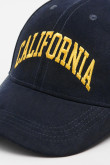 Gorra beisbolera en color azul, con refuerzo, cierre plástico y aplique bordado "California".