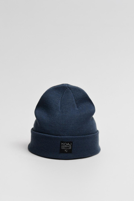 Gorro tejido unicolor con marquilla decorativa en frente