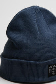 Gorro tejido unicolor con marquilla decorativa en frente