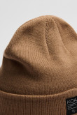 Gorro tejido unicolor con marquilla decorativa en frente