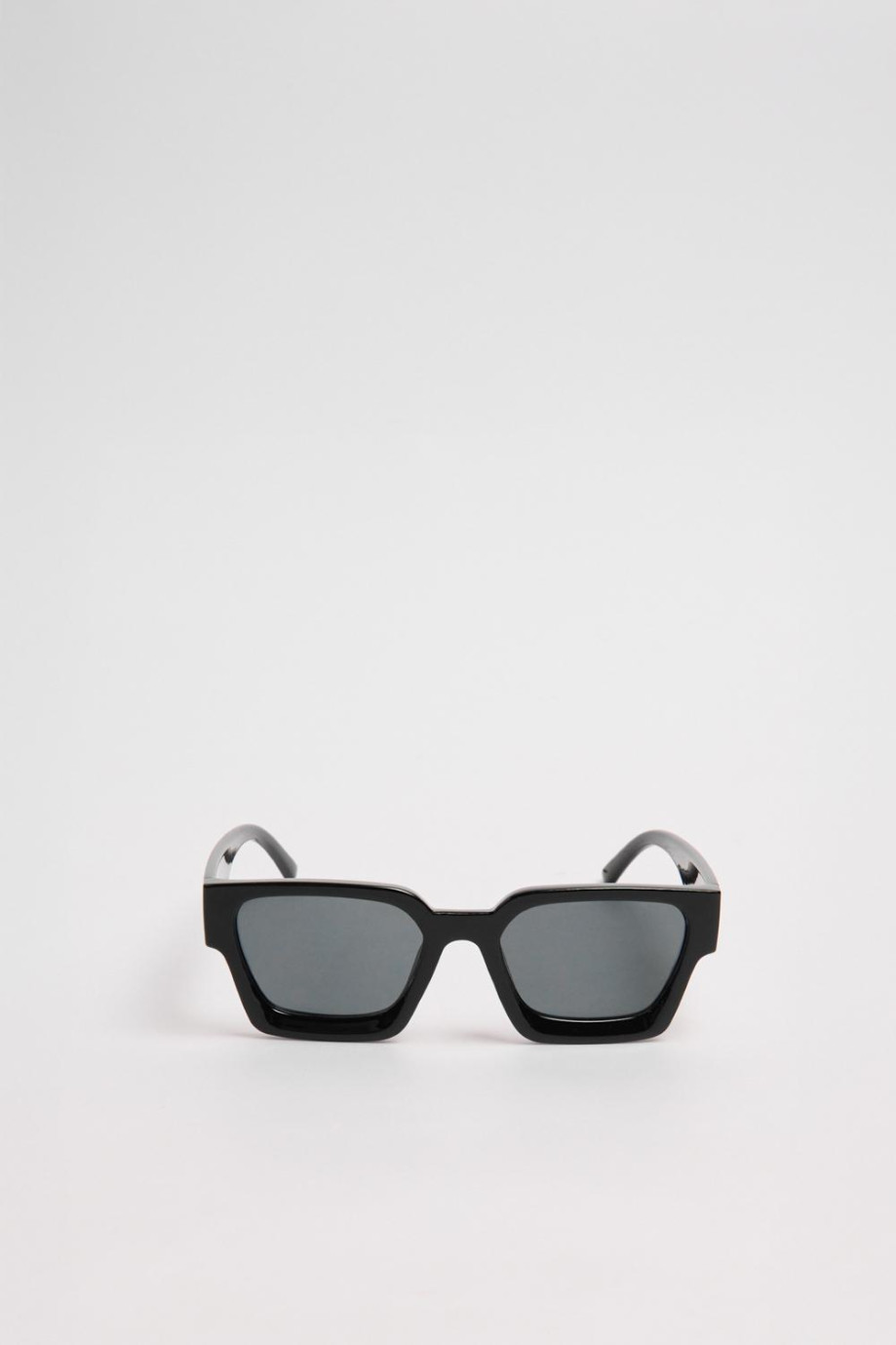 Gafas de sol con marco rectangular en color negro y lentes esfumados en contraste.