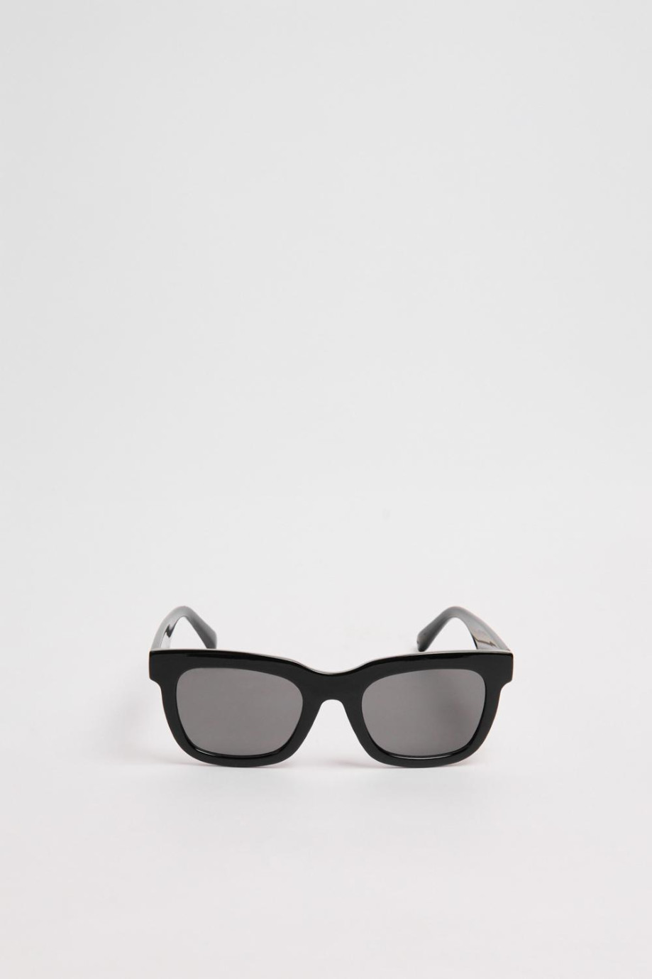 Gafas de sol con marco rectangular en color negro y lentes esfumados en contraste.