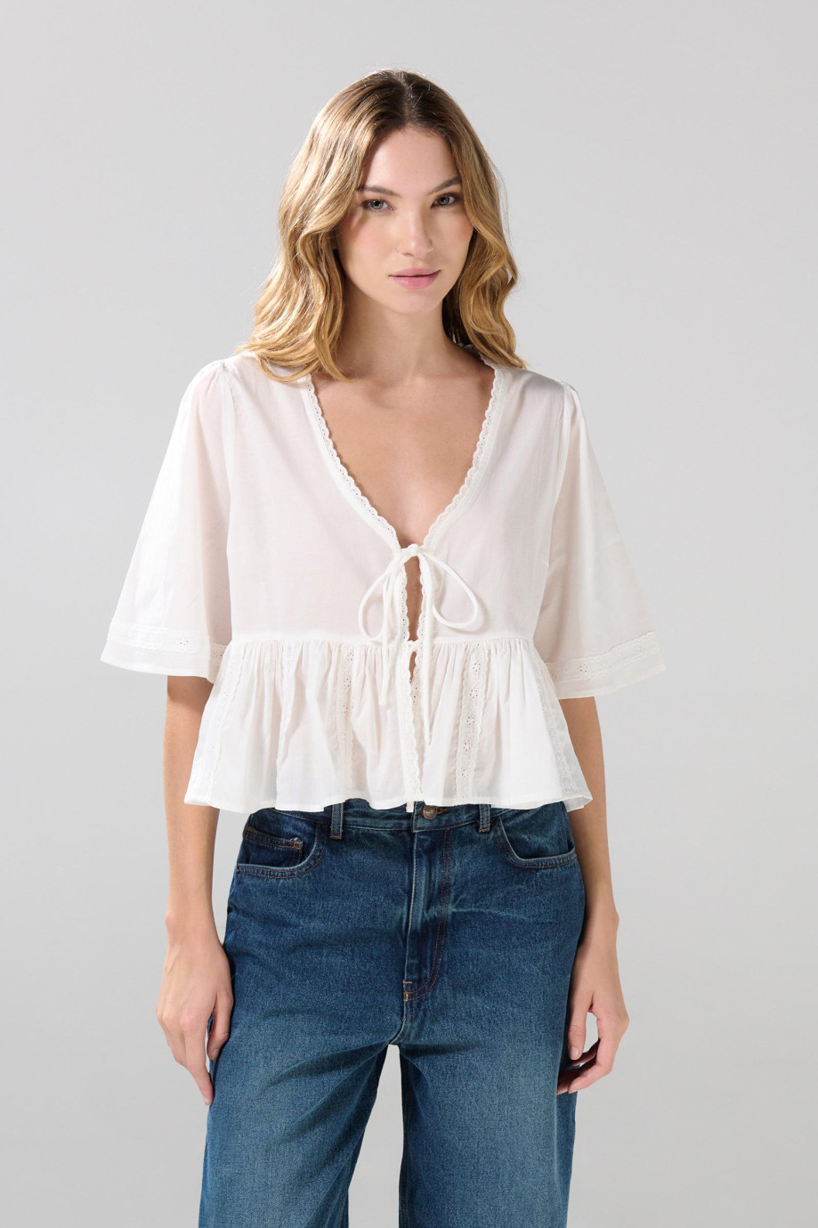 Blusa crema clara con escote V y detalles de encaje