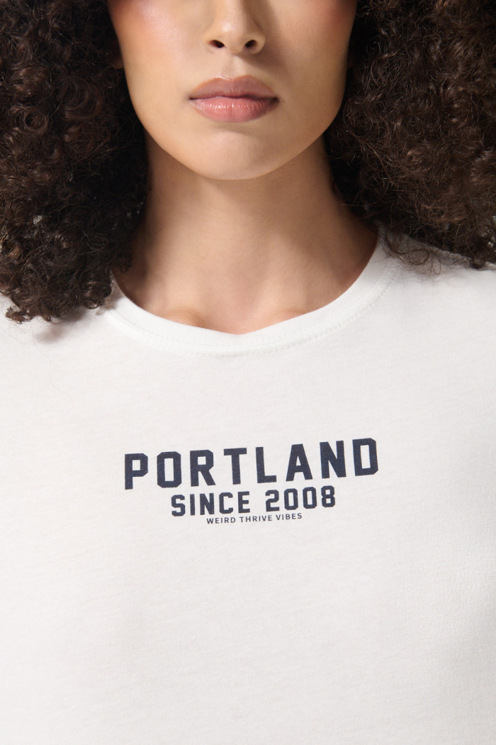 Camiseta crop top crema clara con texto college negro